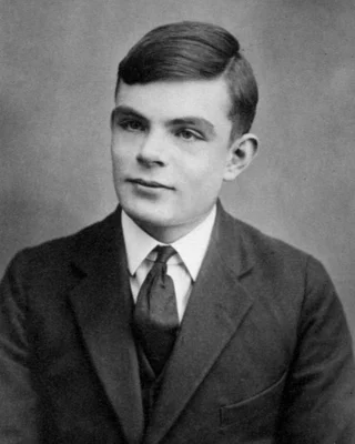 Schwarzweißfoto von Alan Turing mit 16: ein Junge mit gescheiteltem dunklem Haar in Anzug und Krawatte.