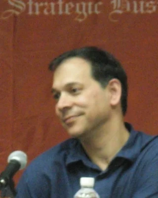Ken Perlin 2007 auf einem Podium: ein Mann mit dunklem Haar in blauem Hemd, lächelnd zur Seite.