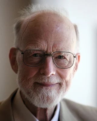 Tony Hoare 2011: ein älterer Mann mit weißem Bart und Brille, freundlich in die Kamera blickend.