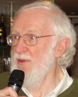 Peter Naur 2008: ein älterer Mann mit weißem Haar, weißem Bart und Brille, im grünen Pullover, spricht in ein Mikrofon.