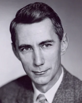 Schwarzweißporträt von Claude Shannon als junger Mann in Anzug und Krawatte.